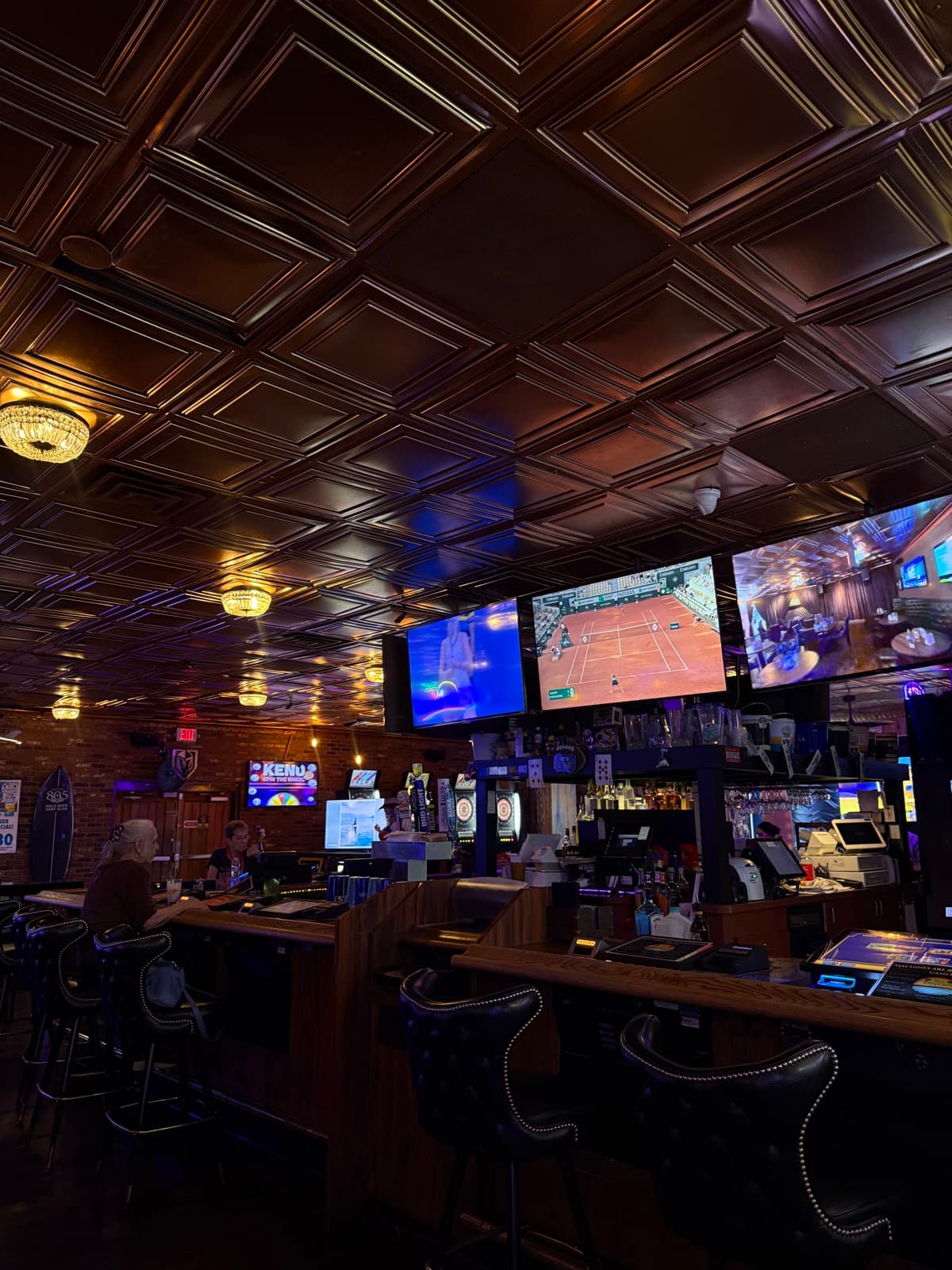 The bar at The Tavern on Rainbow with pressed-tin ceiling and TVs